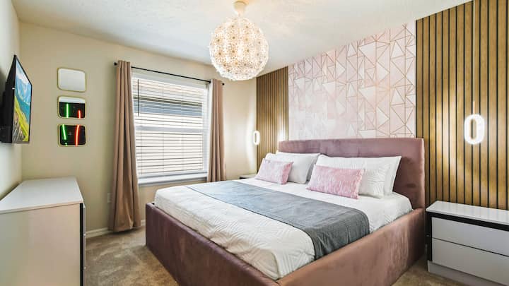 Გასაოცარი საძინებელი გეომეტრიული აქცენტებით, რბილი განათებითა და ხავერდის თეთრეულით.