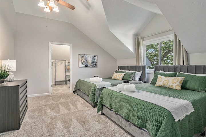 Two Queen Beds Adorned with Green Bedding, Bathed in Natural Light