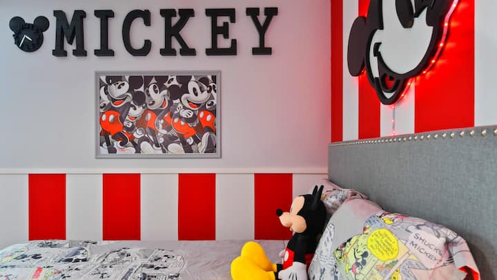 Okúzľujúca spálňa s tematikou Mickey Mouse s výraznými červenými akcentmi a nostalgickou výzdobou.