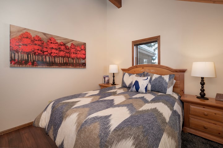 Relájate en tu acogedora habitación con cálidos detalles en madera, ropa de cama geométrica y elegante, y obras de arte otoñales que crean el refugio perfecto.