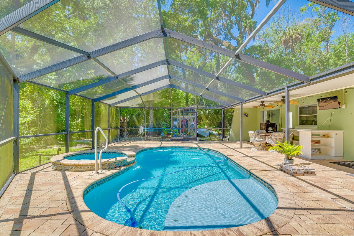 An outdoor area features a screened-in pool with a separate jacuzzi, surrounded by lush greenery. The spacious deck includes a lounge area and a bar, offering a relaxing environment for guests to enjoy.