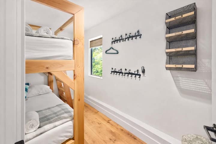 Habitación funcional con literas y área de almacenamiento con ganchos, estanterías y un elegante diseño de estilo costero

