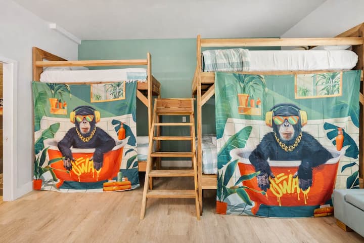 Habitación juvenil con arte personalizado con temática de surf, literas dobles y diseño divertido: un espacio para dormir divertido y enérgico, perfecto para amigos, familias y estancias en centros vacacionales.

