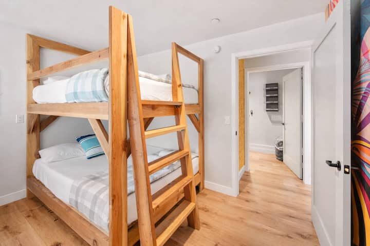 Habitación ordenada con literas de madera maciza, sábanas limpias y fácil acceso al pasillo

