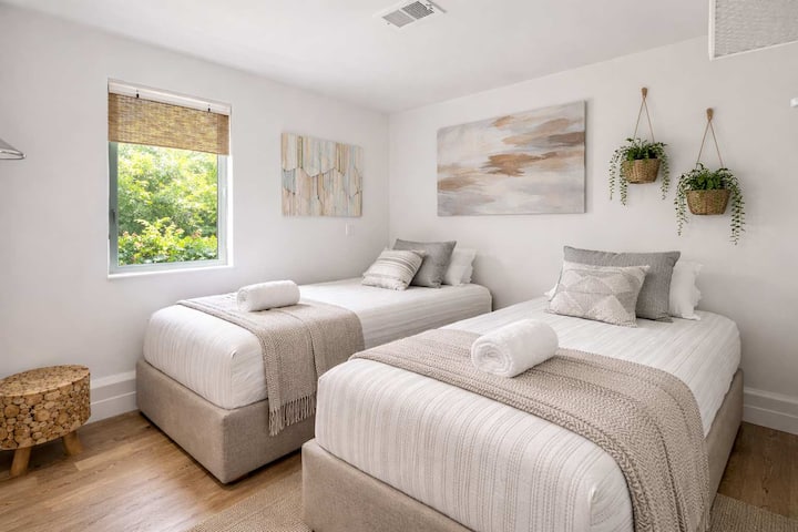 Habitación doble luminosa con dos camas individuales, sábanas limpias y un tranquilo ambiente costero

