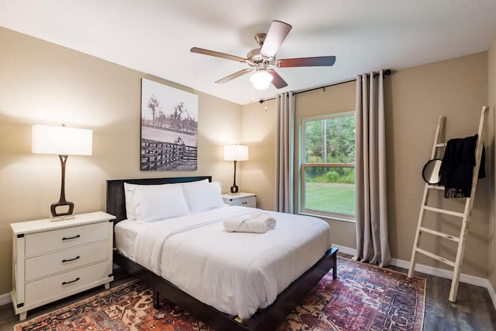 Entra en el tercer dormitorio, un refugio sereno con una lujosa cama tamaño queen, perfectamente posicionada para disfrutar de la luz natural de las ventanas. Adorando la pared, una fotografía de gris captura la elegante gracia de un caballo, haciendo eco de la belleza de la naturaleza.