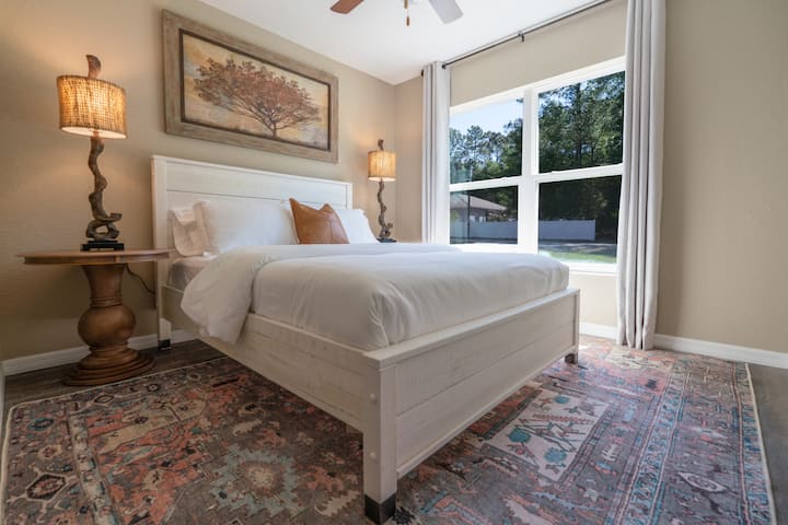 Experimenta la tranquilidad en este primer dormitorio, diseñado alrededor de una acogedora cama tamaño queen que atrae a los baños relajantes. La lámpara rústica emana un ambiente cálido, mejorando el encanto de la serena pintura de árboles en la parte superior. Debajo, trae una alfombra vibrante 