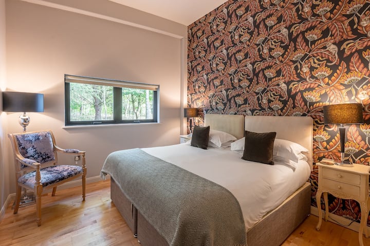 Бутикова спалня с двойно легло (king size), тапети и изглед към градината в Jules Lodge в Бромптън Лейкс.