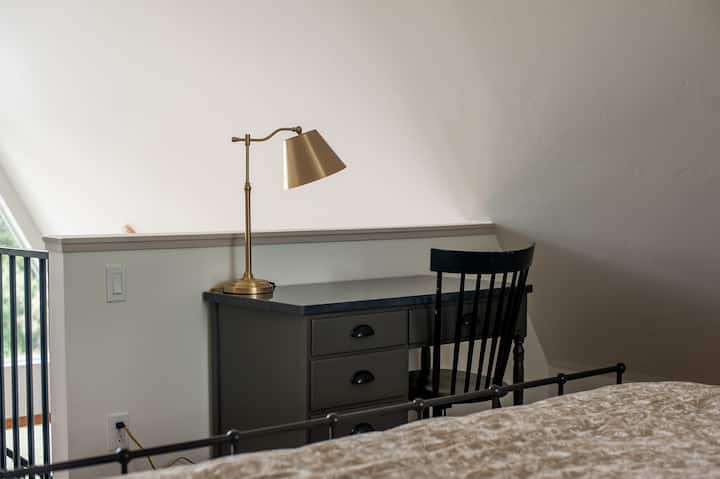 Cozy loft workspace with desk, brass lamp, and soft natural light