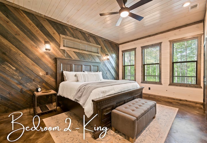 Საძინებელი 2 გთავაზობთ შესანიშნავ საძინებელ სივრცეს დიდი ზომის საწოლით, ელეგანტური სკამითა და ხის ფიცრების სხვადასხვა ფერით მორთული კედლით.