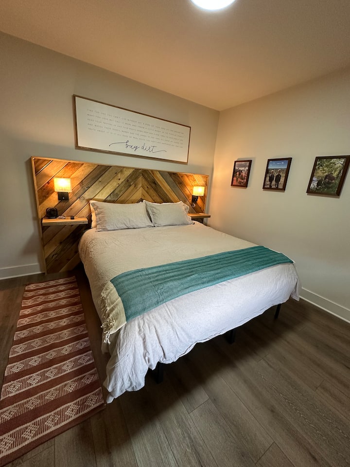 Cama tamaño king con TV montada en la habitación y baño privado adjunto