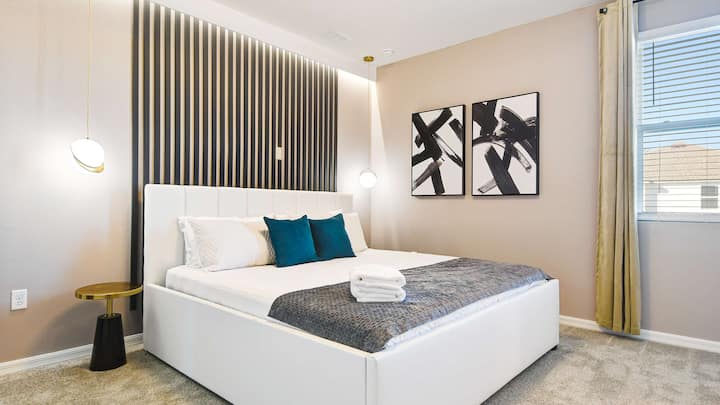 Dormitorio moderno con pared decorativa audaz, iluminación elegante y ropa de cama acogedora.