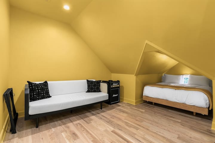 Embrace comfort in the Yellow Room at Flyght. Nestled within its sunlit corners, discover a cozy bed nook and modern amenities like a mini fridge and smart TV.  Not Pictured: Recently added small balcony off the room!