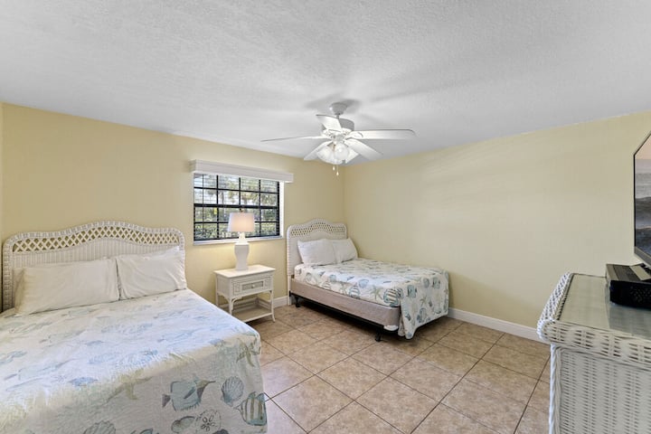 Pohodlná spálňa pre hostí s dvoma manželskými posteľami, ideálna na pokojný nočný spánok po dni plnom zábavy na pláži.