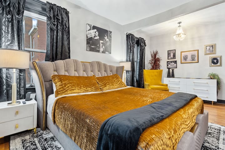 Vågn op i luksus i dette soveværelse på øverste etage med kingsize-dobbeltseng, guldfløjlssengetøj, elegante sorte gardiner og Art Deco-detaljer – perfekt til et stilfuldt ophold i Kansas City.