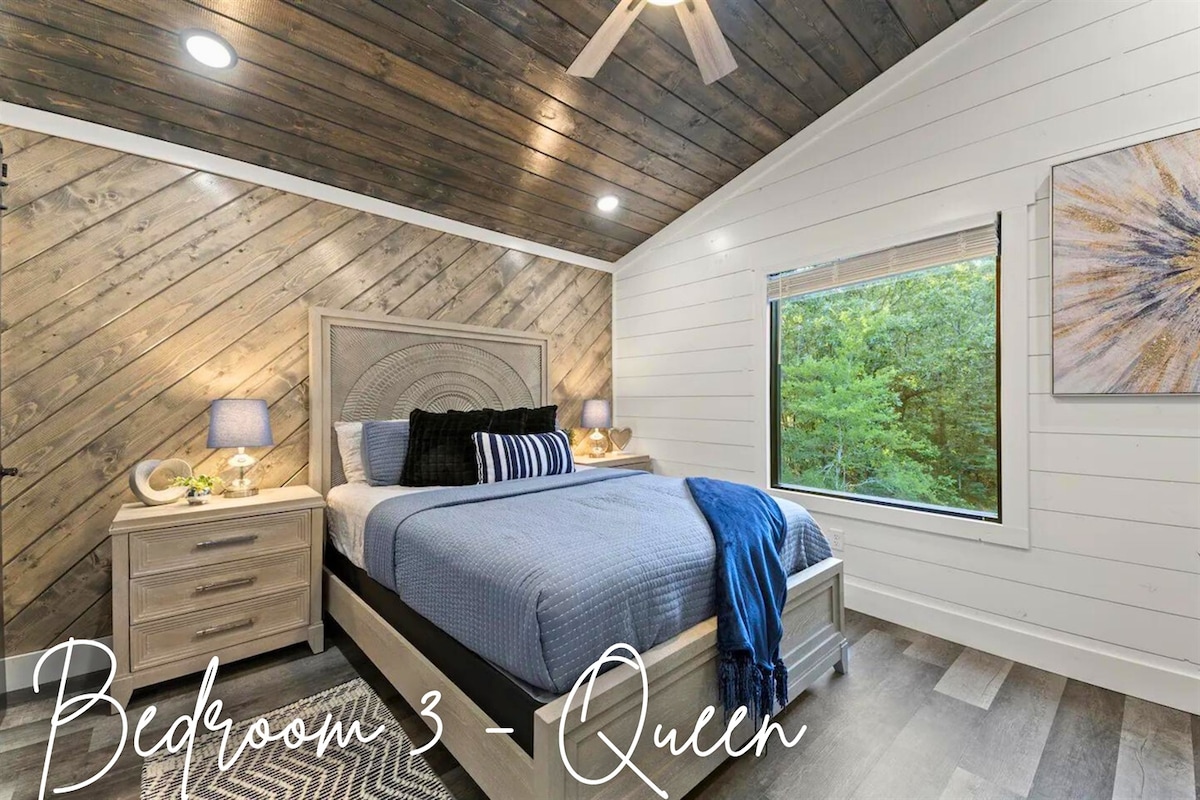 Acogedor dormitorio queen con decoración elegante, resaltado por una obra de arte única y tranquilas vistas a los pinos.