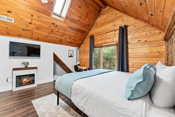 El dormitorio más grande de arriba, esta habitación tiene una cama tamaño king, tragaluz y un hermoso ventanal. Relájate con la luz de una chimenea o encuentra algo en la televisión (Netflix y Youtube TV incluidos).