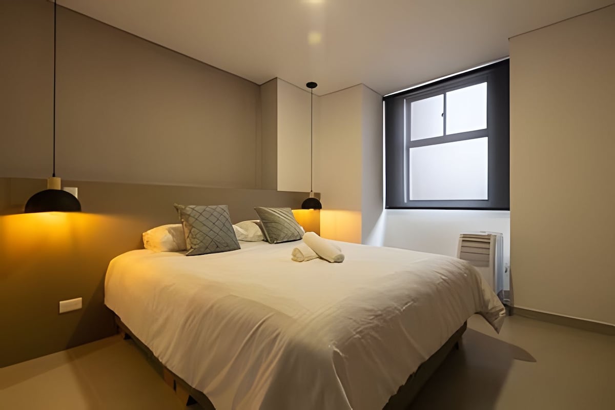 Bedroom 2 features a comfortable Double bed, a cozy room with a portable air conditioner, a table lamp, and a private bathroom, offering comfort and privacy.