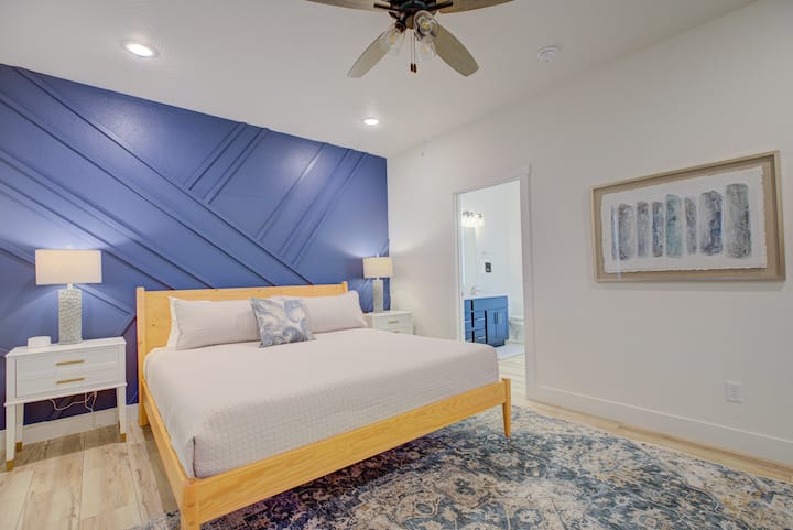 Dormitorio 1: suite King con pared personalizada, elegante silla de huevo, televisor inteligente de 55pulgadas y baño privado con tocador doble, ducha de puerta de vidrio con entorno de mármol cultivado y lujosa bañera independiente.