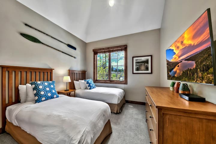 Twin beds with wooden slatted headboards, blue patterned pillows, and canoe paddles mounted above.
