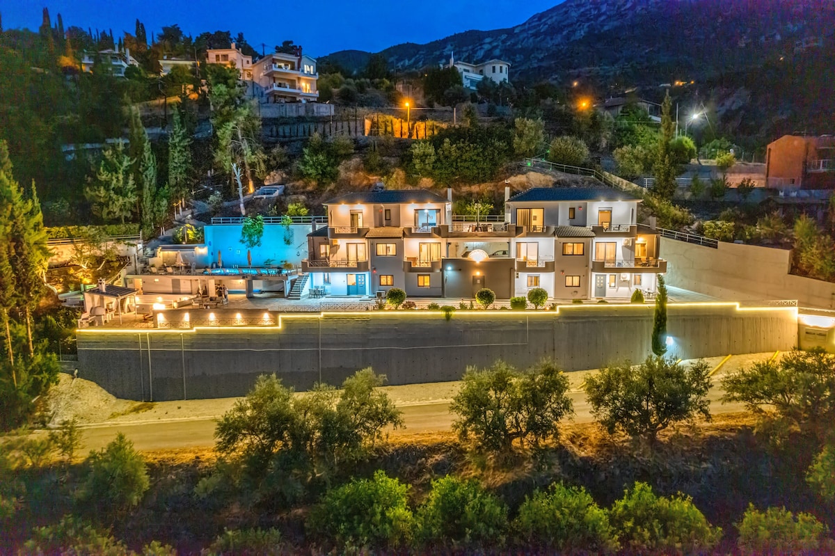A scenic view of Onar Zin is presented, featuring multiple modern properties lined along a hillside. Soft outdoor lights illuminate the walkways, while a private swimming pool is visible in the background, creating a serene ambiance against a twilight sky.