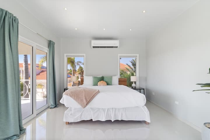 Пространа спална соба на вилата во Норд Аруба - Удобен брачен кревет - Елегантно дизајнирана соба - Прекрасни обоени ѕидови со декорација - Величествени ламби за на маса - Убава и чиста постелнина - Големи прозорци со прекрасен поглед - достапен е телевизор и Netflix