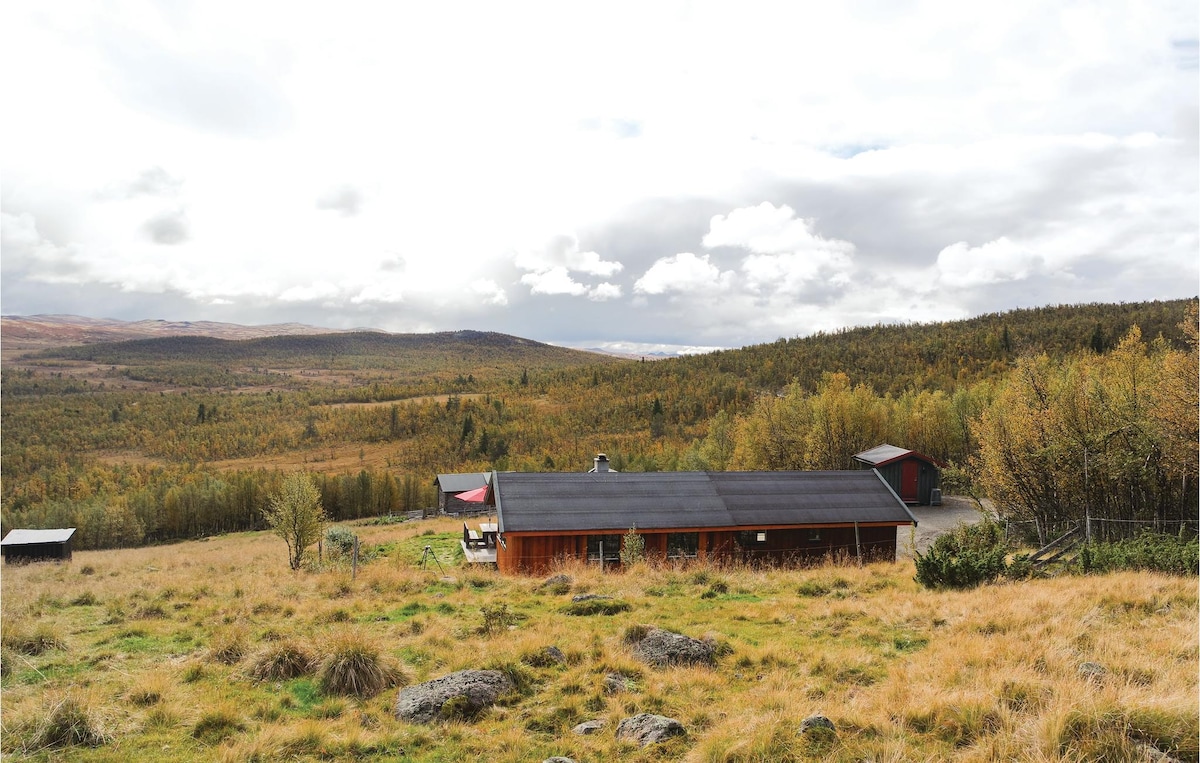A spacious log cabin is set against a backdrop of rolling hills and vibrant greenery. The surrounding landscape features soft grasses and scattered rocks, with distant mountains visible under a partly cloudy sky.