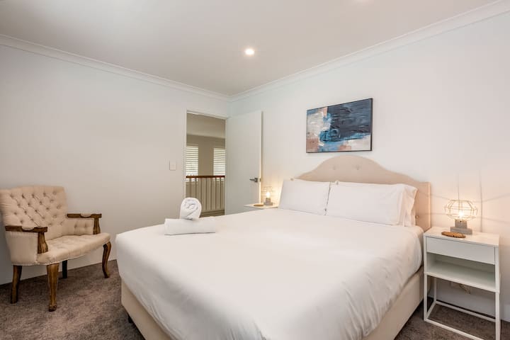 Un espacio bellamente diseñado con una cama tamaño queen con lujosa ropa de cama, iluminación suave y una decoración elegante. Este refugio sereno es ideal para relajarse después de un día de exploración.