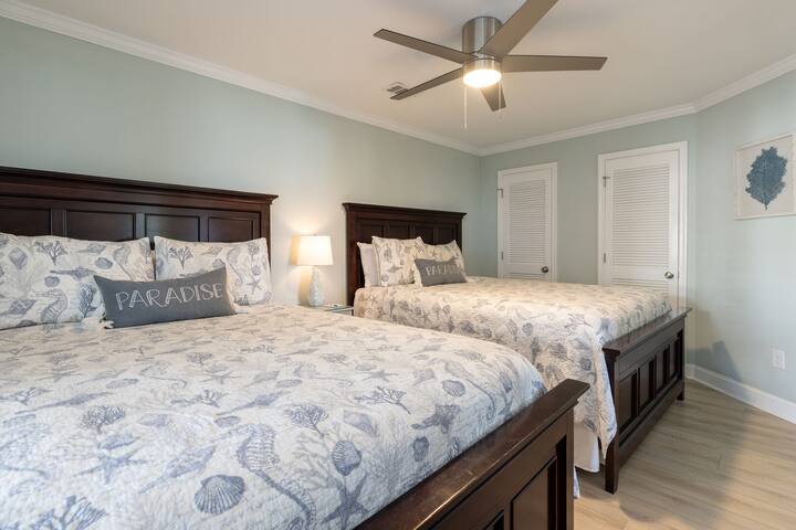 توفر غرفة نوم الضيوف الواسعة هذه سريرين مجهزين بشكل جميل مع إطارات خشبية داكنة مطابقة وأغطية مستوحاة من الساحل.