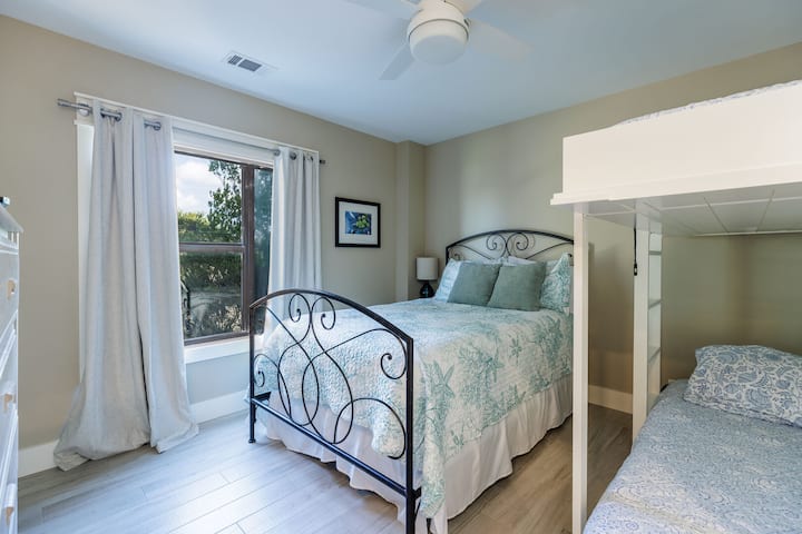 Large windows frame leafy views, creating a peaceful backdrop for rest and relaxation.