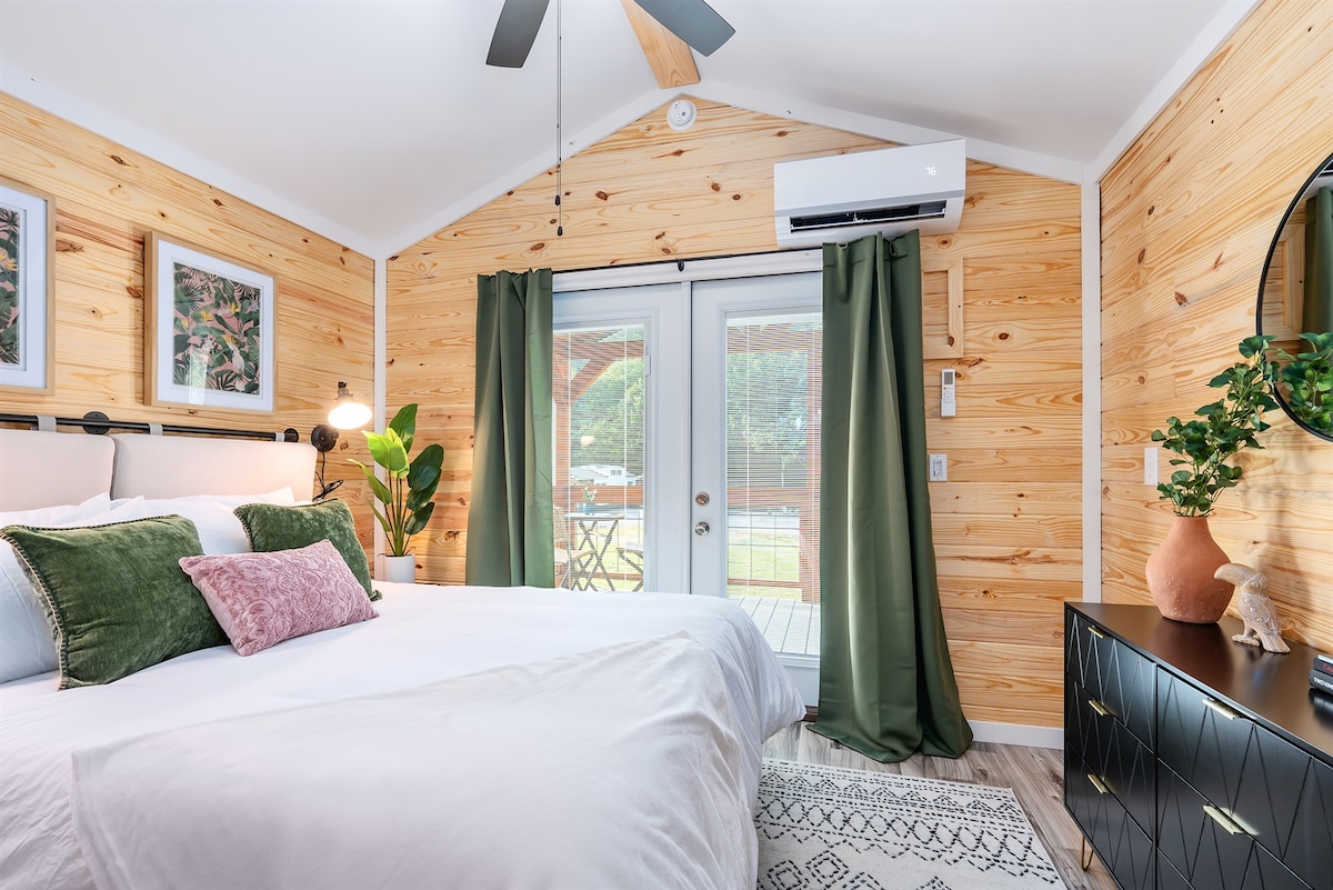 Luksuzna spavaća soba s bračnim krevetom i posteljinom koja je otvorena za privatnu stražnju terasu za zalaske sunca.