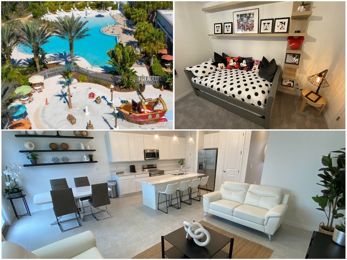 An aerial view of the community pool showcases a large, inviting area surrounded by lush palm trees and vibrant water slides. Adjacent, a cozy Mickey and Minnie Mouse-themed bedroom features a playful polka-dotted bed, decorative cushions, and wall art. Finally, a bright dining area and kitchen present a modern design with sleek white furniture and ample seating.