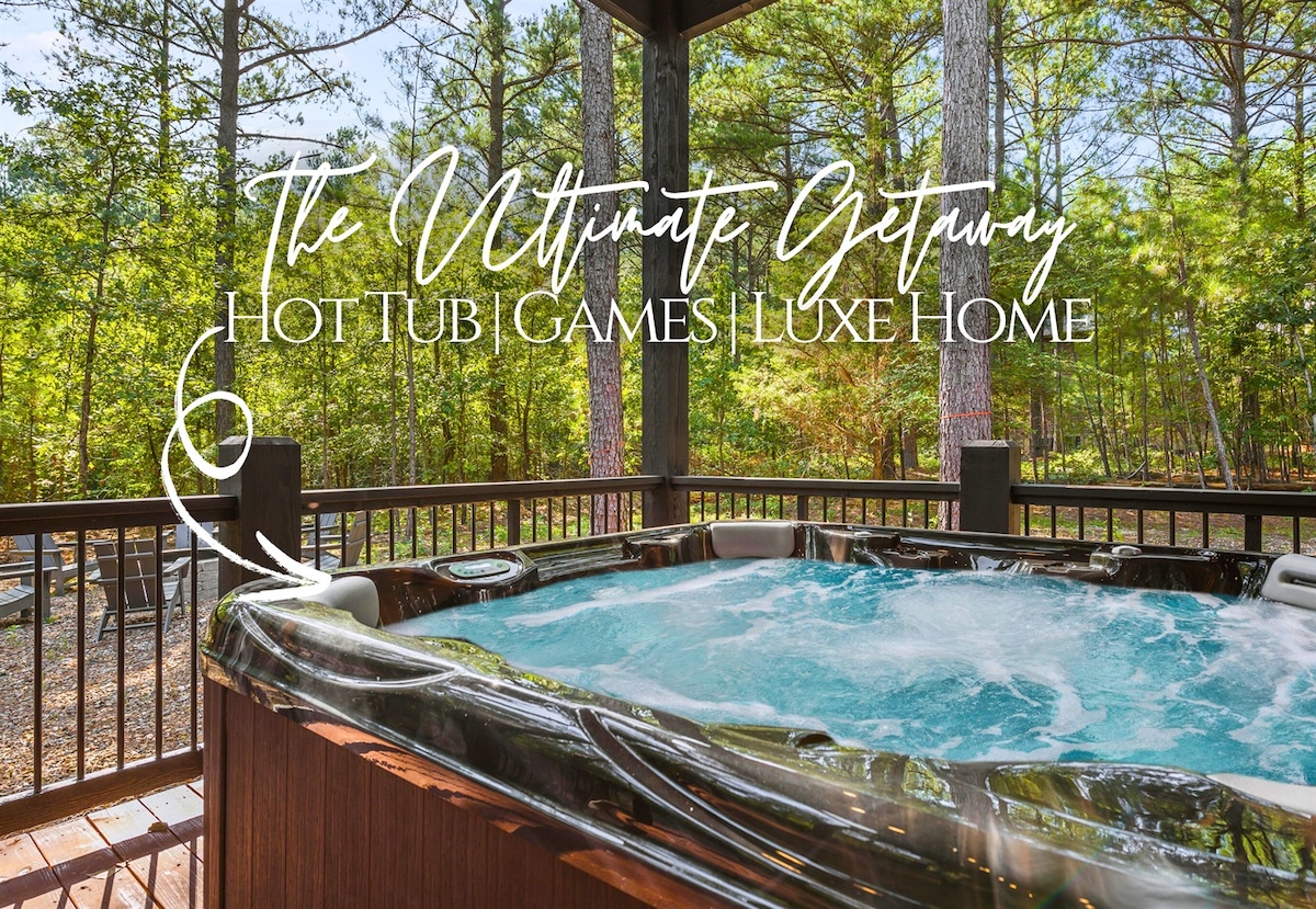 A hot tub is nestled on a covered deck, surrounded by trees. The jets are bubbling above the water, creating a soothing atmosphere. The wooden railing complements the rustic feel, providing a safe space to unwind. Natural light filters through the foliage, enhancing the serene setting.