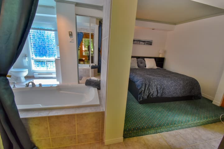 Chambre style loft avec lit king, sdb ouverte, salon et cuisine