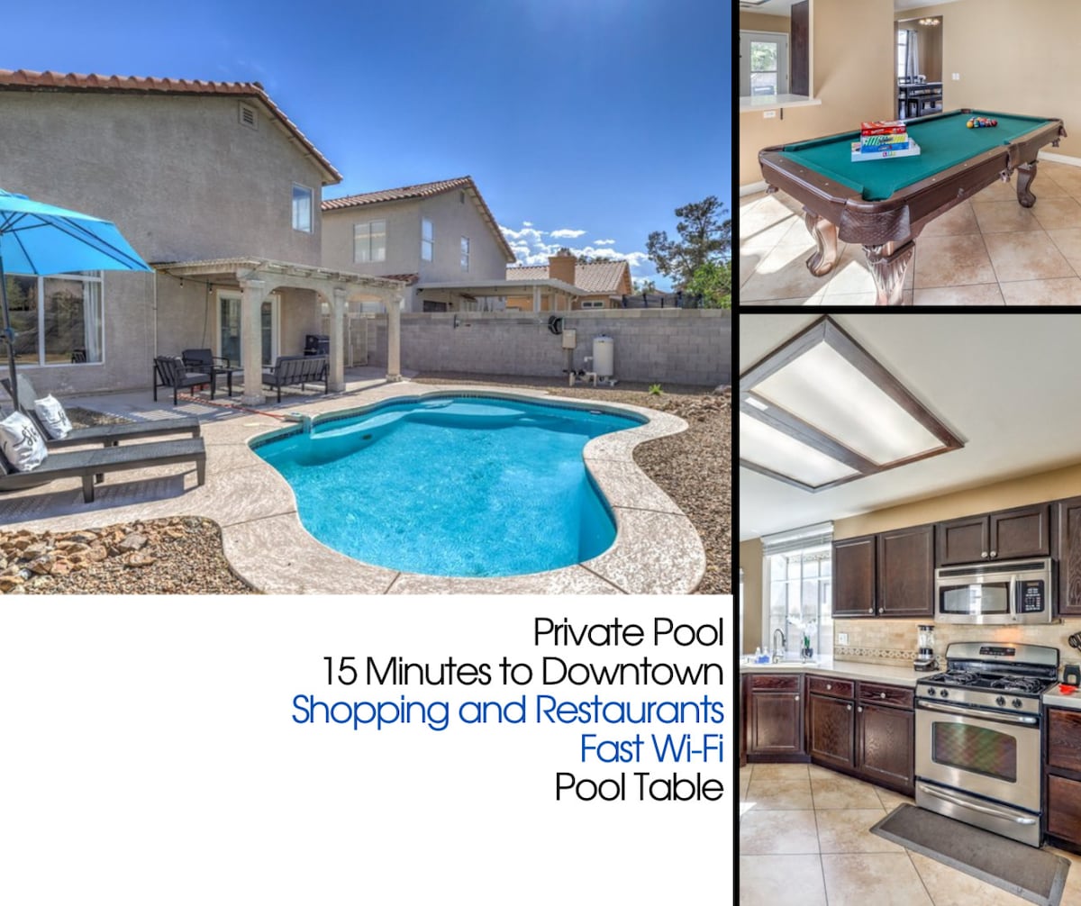 The image showcases a private pool surrounded by a stone patio and outdoor seating area, complemented by an umbrella providing shade. A pool table is visible inside, along with a modern kitchen featuring dark cabinetry and stainless-steel appliances, enhancing the home’s entertainment options.