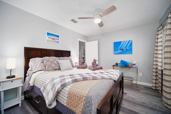 Cómodo dormitorio de invitados con cama tamaño queen, ventilador de techo y decoración luminosa.