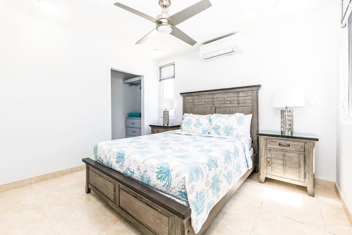 Cómodo dormitorio tamaño queen con muebles modernos y decoración de inspiración isleña.