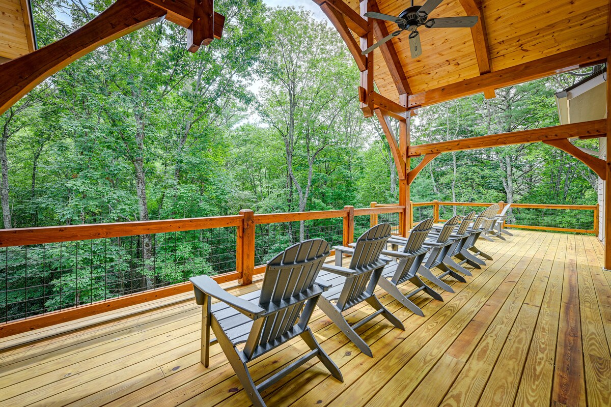A spacious back deck features multiple Adirondack chairs arranged for relaxation, surrounded by a wooden railing. Towering trees create a serene backdrop, enhancing the connection with nature while providing shade and privacy.