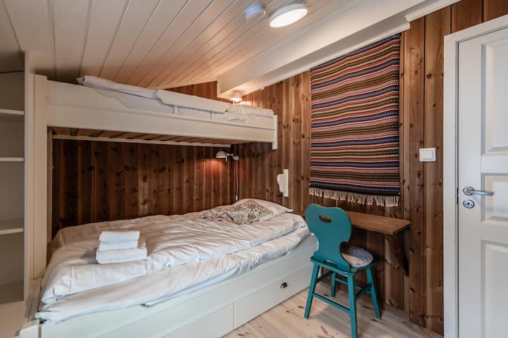 Chambre confortable avec lits superposés, bureau intégré et décor scandinave traditionnel, parfaite pour les enfants ou les voyageurs supplémentaires.