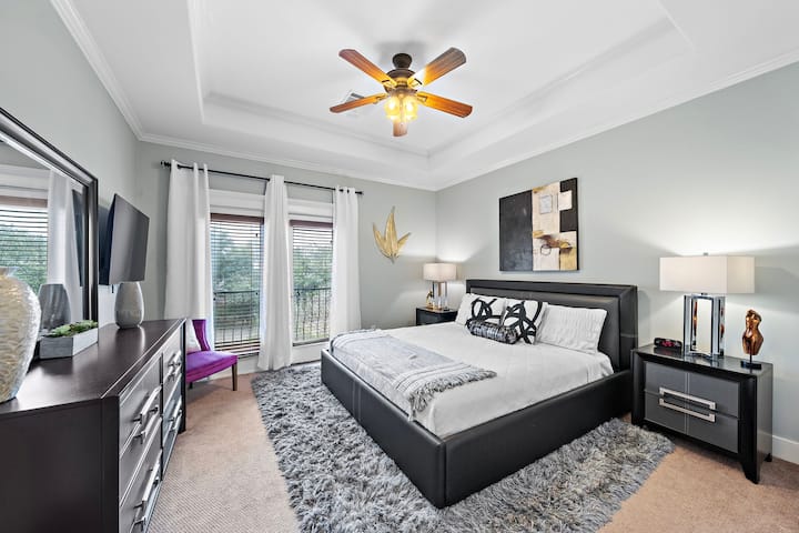 Chumba cha kulala cha msingi kilicho na kitanda na roshani ya ukubwa wa kifalme.