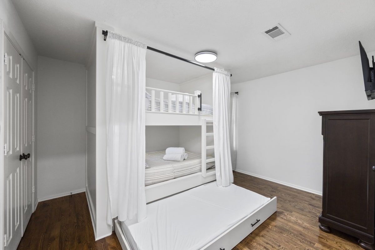Bunk room with two built-in queen beds plus a twin trundle, complete with privacy curtains for added comfort and flexibility for families or groups.