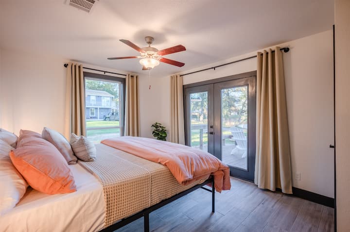 ホワイトハウスの寝室2：ベシークリークの景色と屋外の席につながる専用のフレンチドアを備えた、快適なキングサイズのベッド2台が眠っています。 