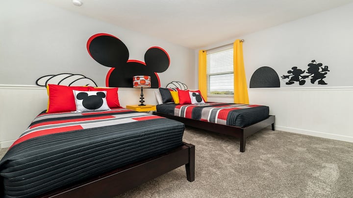 ¡Divertida habitación con temática de Mickey Mouse con camas individuales y decoración vibrante!