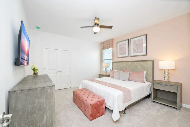 Elegante dormitorio con una cama tamaño king y acentos de color rosa suave