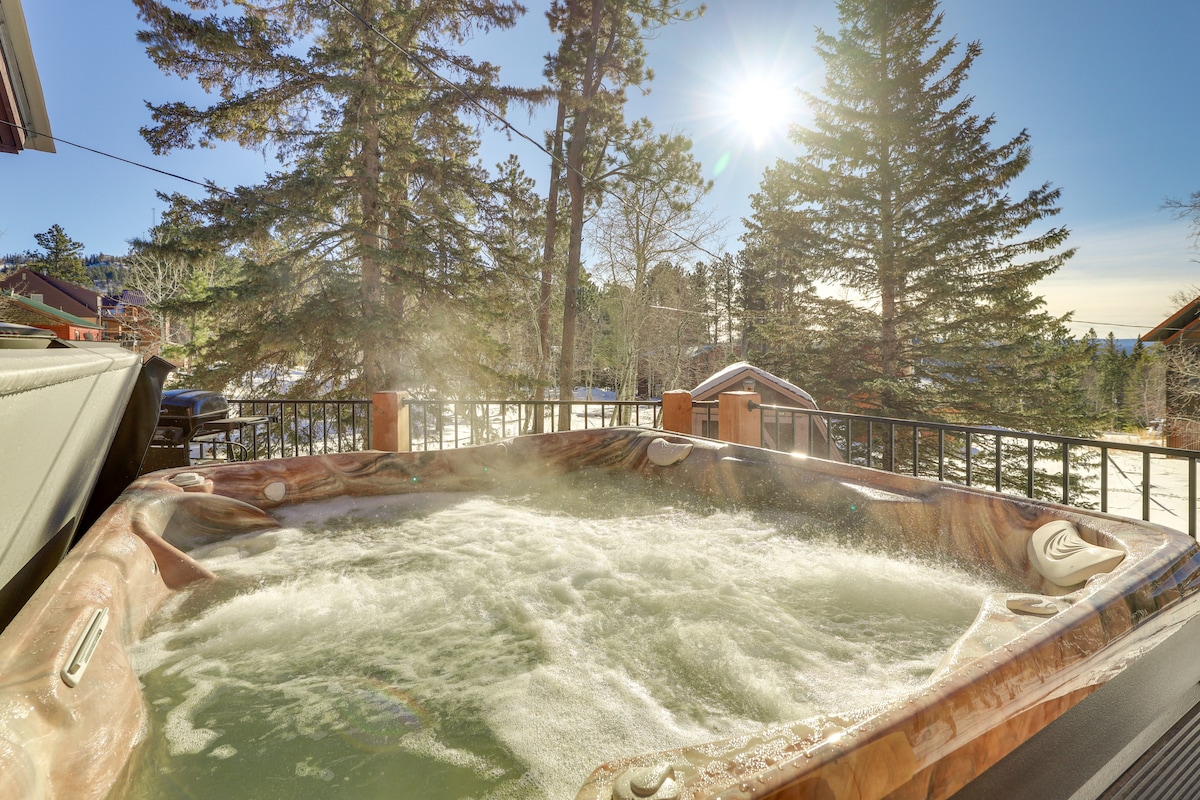 A hot tub is positioned on a private deck, surrounded by tall pine trees. Sunlight filters through the branches, creating a serene atmosphere. The bubbling water invites relaxation while offering a panoramic view of the natural surroundings.