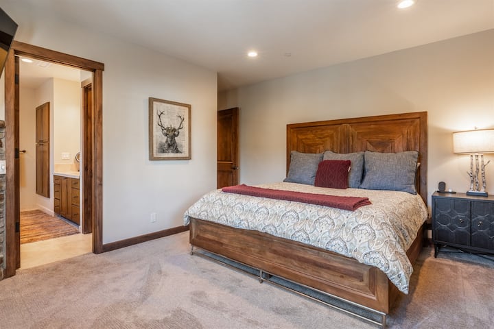 Una espaciosa suite King en Bear’s Den ofrece un refugio tranquilo con ropa de cama cómoda y un relajado estilo de montaña.