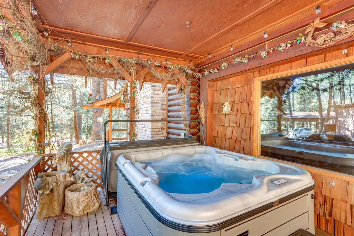 A private hot tub is positioned on a wooden deck, surrounded by nature. Walls are adorned with rustic wooden shingles, and soft lighting creates a pleasant ambiance. Nearby, large windows provide a view of the outdoor surroundings, enhancing the serene atmosphere.