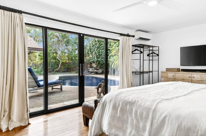 Wake up to your own private pool paradise through floor-to-ceiling glass doors that open your bedroom to tropical serenity.