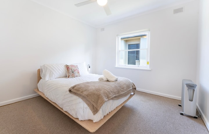 Una habitación bien presentada con tonos suaves y una cama doble con ropa de cama blanca y fresca.