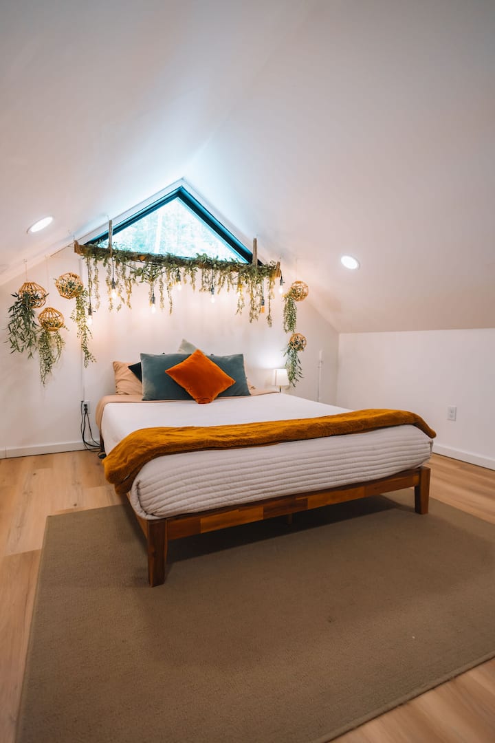 Loft bedroom with greenery and lights – a romantic touch.